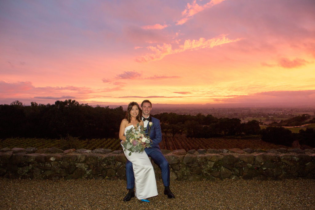 Newlyweds in front of vineyards, hills and sunset at Paradise Ridge winery