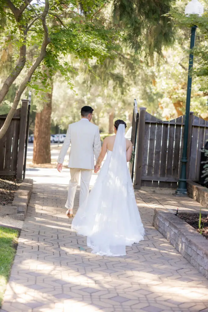 Bride and groom walking away through the garden gates.
