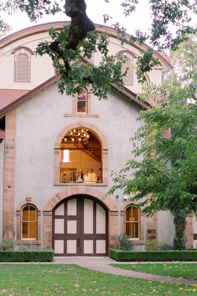 Charles Krug Winery Carriage house viewed from the lawn on with trees surrounding and guests dining in a window upstairs